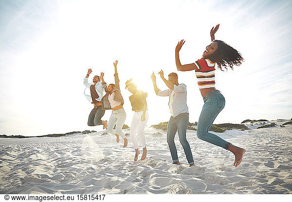 Portrait playful  energetic young friends jumping for joy on sunny summer beach
