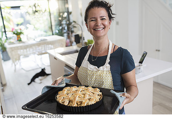 Portrait proud woman with baked lattice pie in kitchen