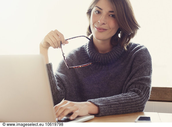 Portrait selbstbewusste brünette Frau mit Brille und Laptop