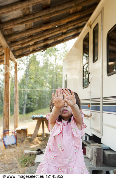 Portrait shy girl hiding face with hands outside rural camper