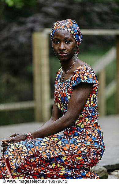 Portrait sit woman looking camera wearing african dress outdoor
