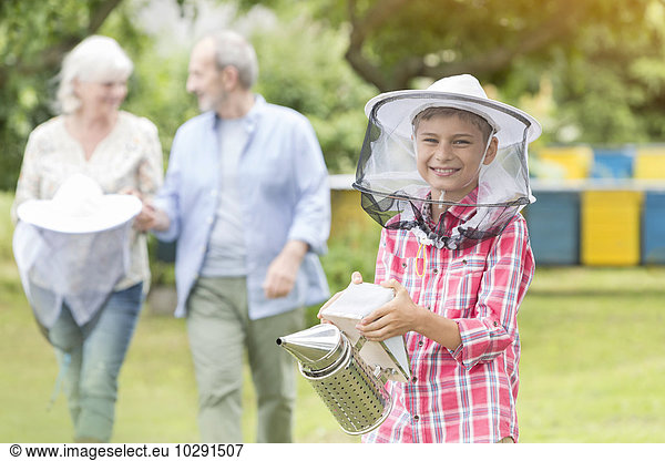 Portrait smiling boy in beekeeper hat holding smoker