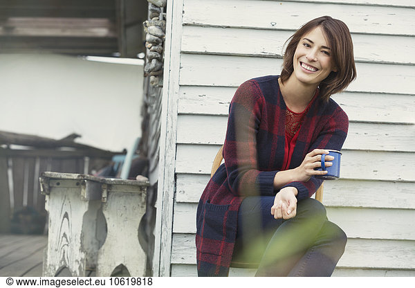 Portrait smiling brunette woman drinking coffee on porch