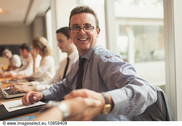 Portrait smiling businessman handshaking in conference room meeting