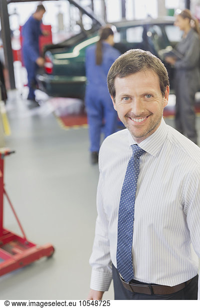 Portrait smiling businessman in auto repair shop