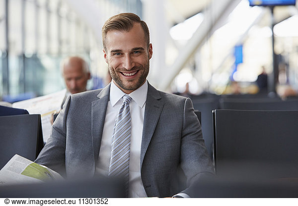 Portrait smiling businessman reading newspaper in airport departure area