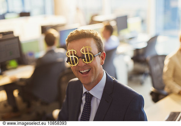 Portrait smiling businessman wearing dollar sign sunglasses in office