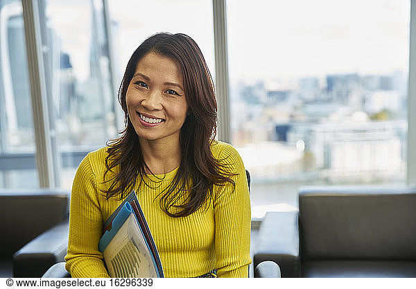 Portrait smiling businesswoman with paperwork in office