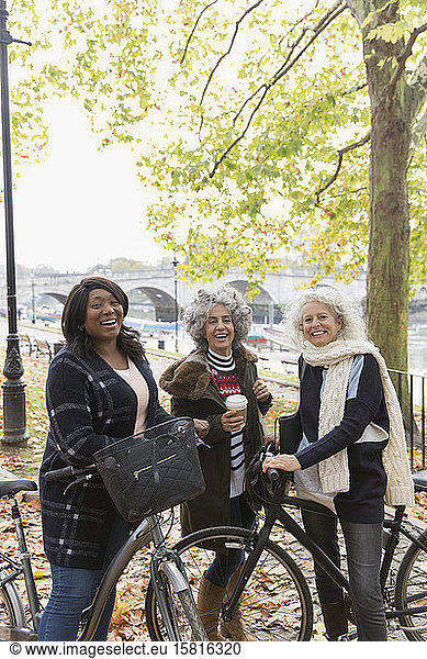 Portrait smiling  confident active senior women friends with coffee and bicycles in autumn park