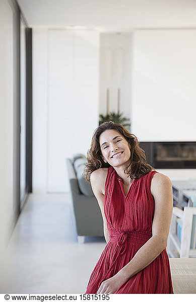 Portrait smiling  confident brunette woman in red dress at home