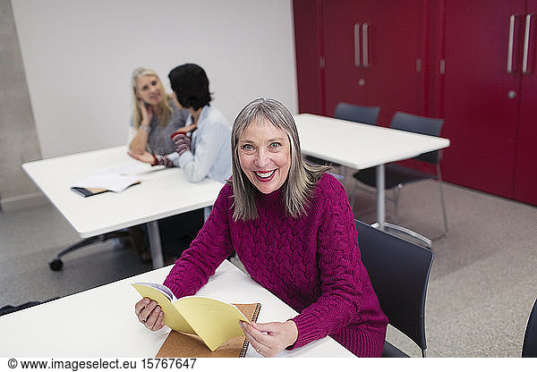 Portrait smiling  confident female community college student reading in classroom
