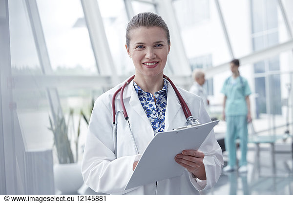 Portrait smiling  confident female doctor with clipboard in hospital