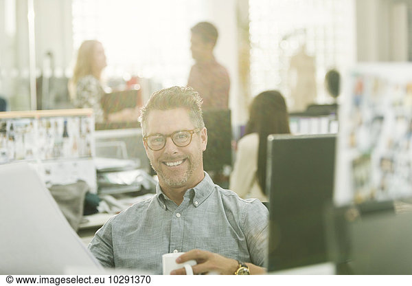 Portrait smiling fashion designer drinking coffee in office