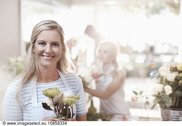 Portrait smiling florist holding spider mums in flower shop