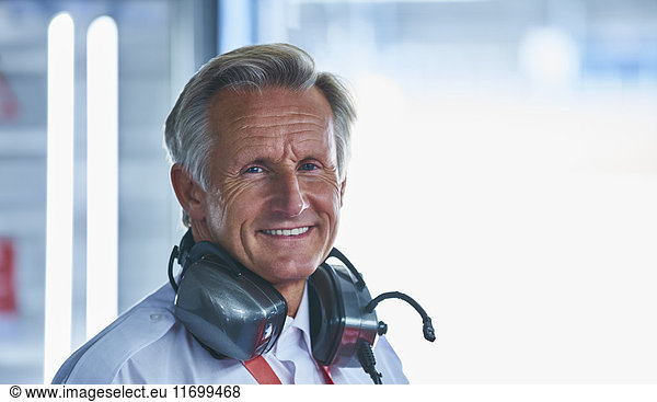 Portrait smiling formula one racing manager with headphones