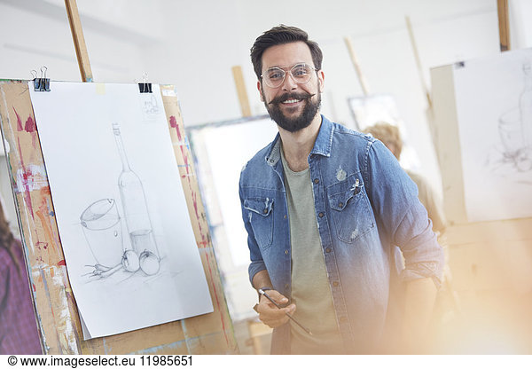 Portrait smiling male artist with beard sketching in art class studio