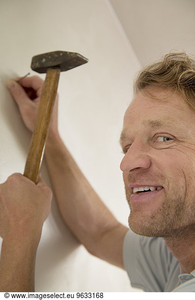 Portrait smiling man working hammer nail wall