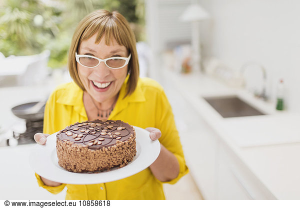 Portrait smiling mature woman holding chocolate cake