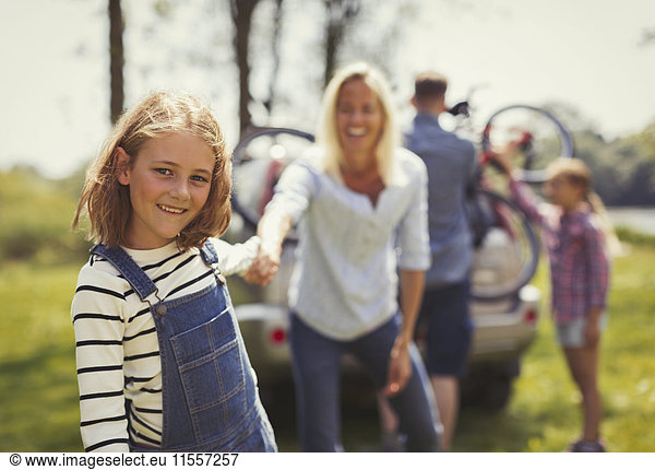 Portrait smiling mother and daughter holding hands outside car