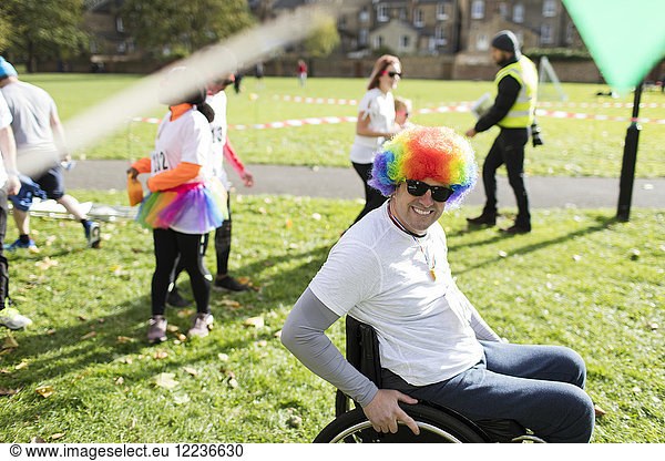 Portrait smiling  playful man in wheelchair wearing clown wig at charity race in sunny park