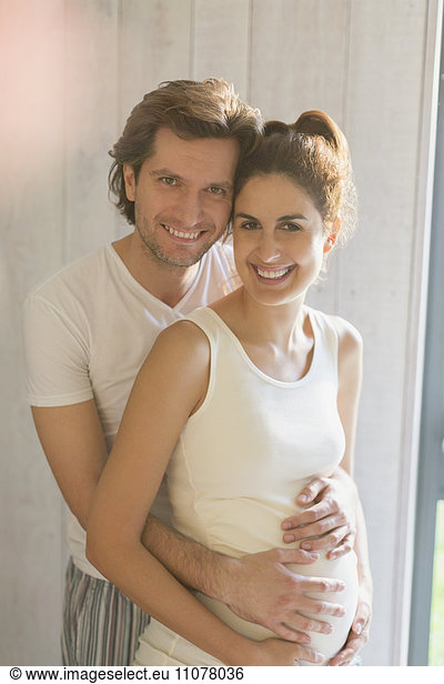 Portrait smiling pregnant couple hugging