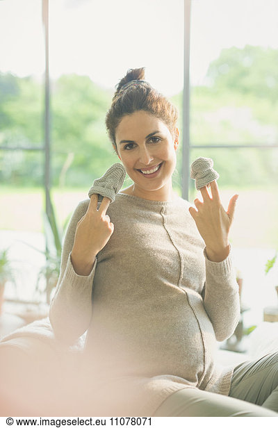 Portrait smiling pregnant woman holding baby booties