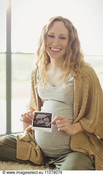 Portrait smiling pregnant woman holding ultrasound