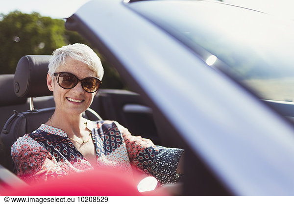Portrait smiling senior woman in sunglasses driving convertible