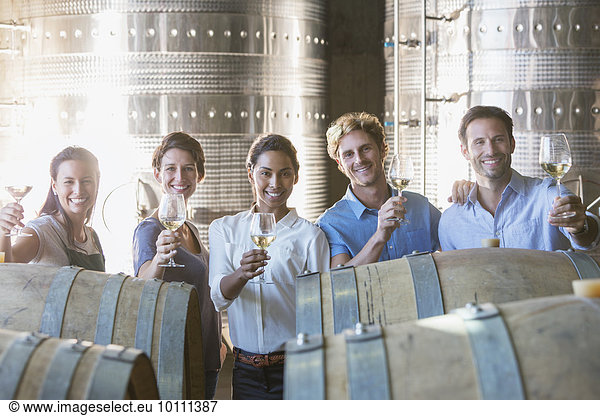 Portrait smiling winery employees barrel tasting in cellar
