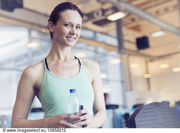 Portrait smiling woman drinking water at gym
