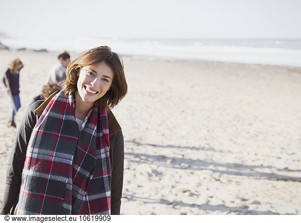 Portrait smiling woman in plaid scarf on sunny beach
