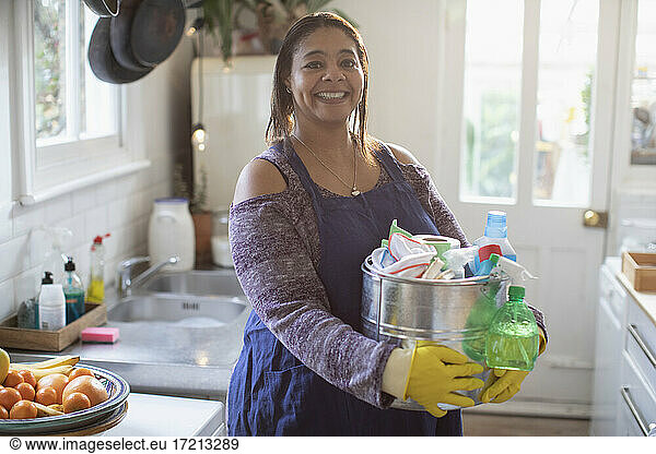 Portrait smiling woman with cleaning supplies in kitchen