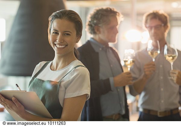 Portrait smiling woman with clipboard working in wine tasting room