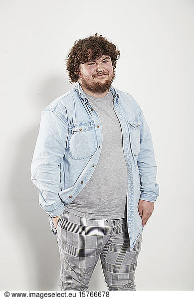 Portrait smiling young man in denim shirt and plaid pants