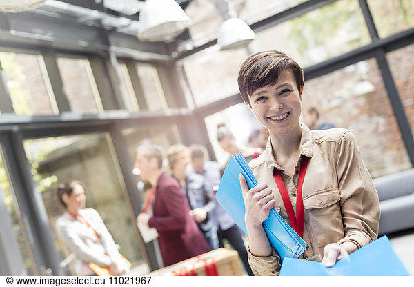 Portrait smiling young woman handing out packets at conference