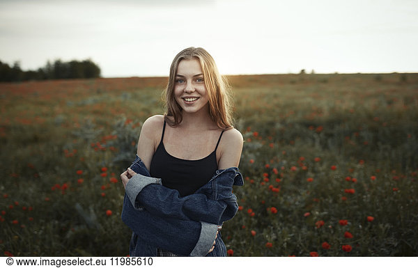 Portrait smiling young woman in rural field with wildflowers