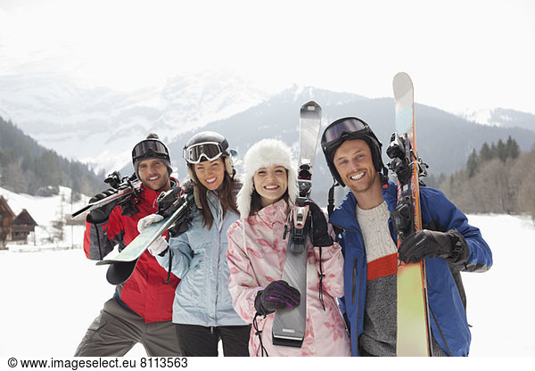 Portrait von lächelnden Freunden mit Skiern im Schneefeld