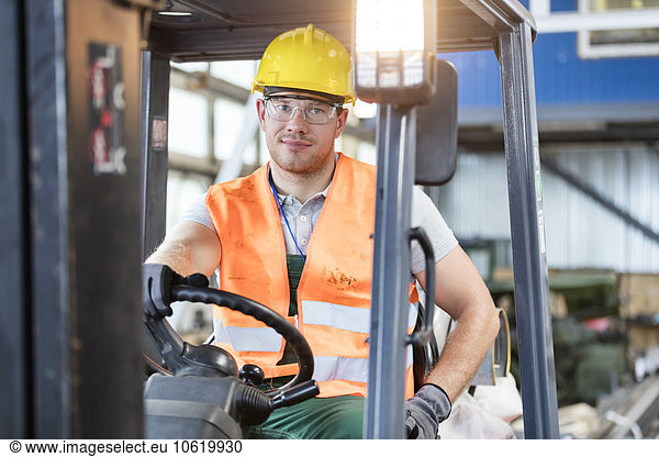 Portrait worker driving forklift in factory