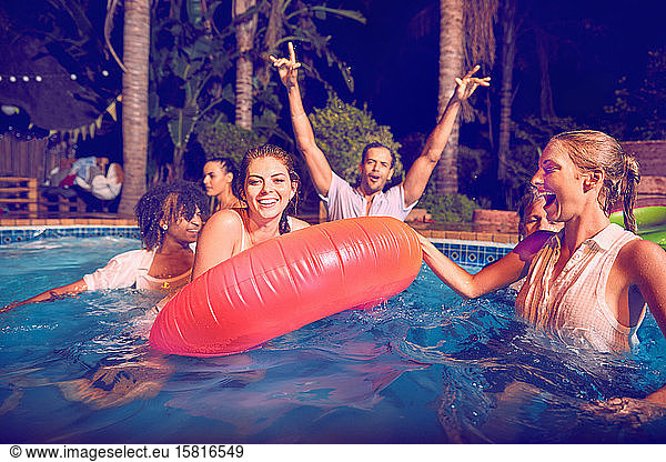 Portrait young friends playing in swimming pool at night
