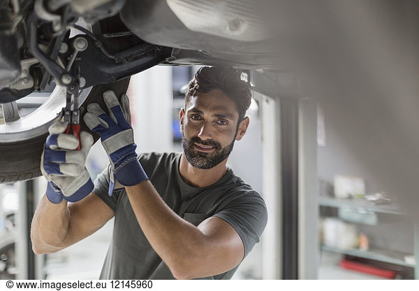 Portrait zuversichtlich männlich Kfz-Mechaniker arbeiten unter dem Auto in der Kfz-Werkstatt