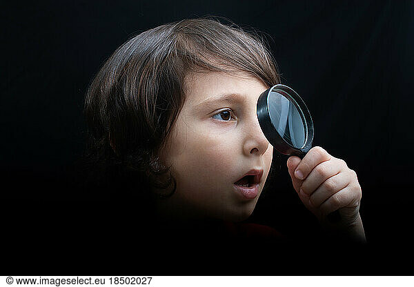 Portrat of a young boy looking through the magnifying glass