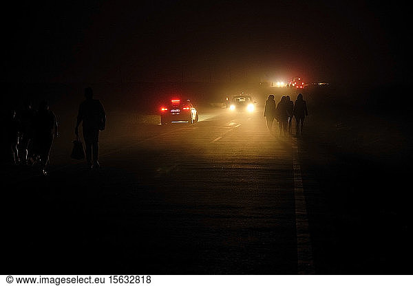 Portugal  Algarve  Cars passing silhouettes of four people walking along road in Cape Saint Vincent at night
