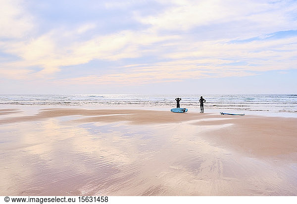 Portugal  Algarve  Silhouettes of two surfers standing on Cordoama beach