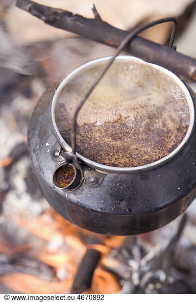 Pot with coffee hanging on stick
