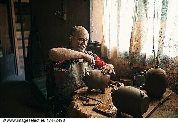 Potter making piggy bank in pottery
