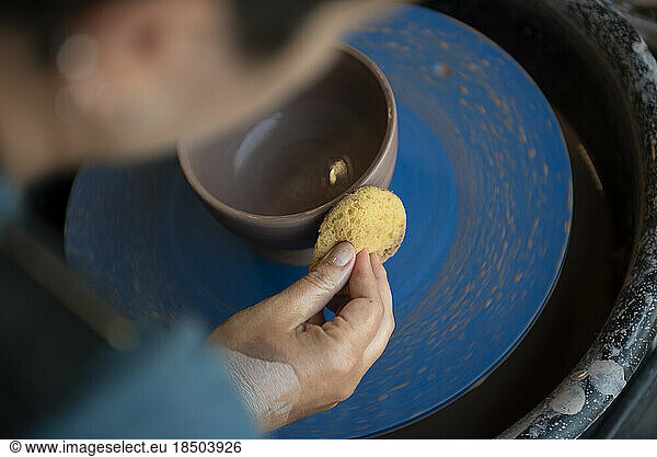 Potter smoothing a clay bowl on pottery wheel