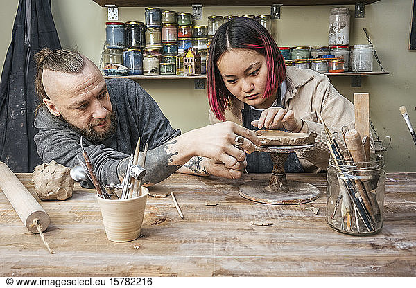 Potter teaching trainee in workshop