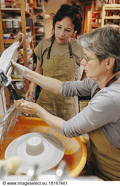 Potters working together on pottery wheel at ceramics workshop