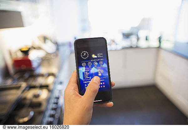 POV Man adjusting climate control from smart phone in kitchen