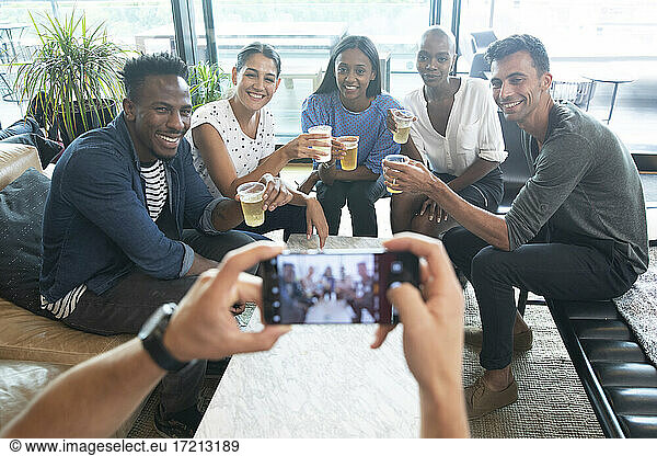 POV man with smart phone photographing friends drinking beers